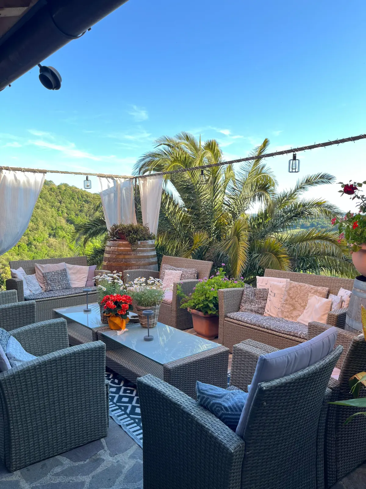 La terrazza panoramica con divanetti, palme e vista sulla Maremma